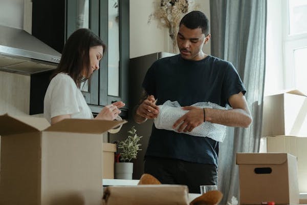 Man and woman packing boxes with tape and bubble wrap