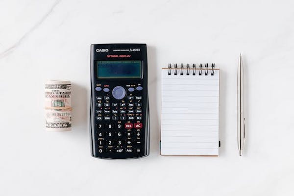 A calculator, notepad, pen and some money on a white background